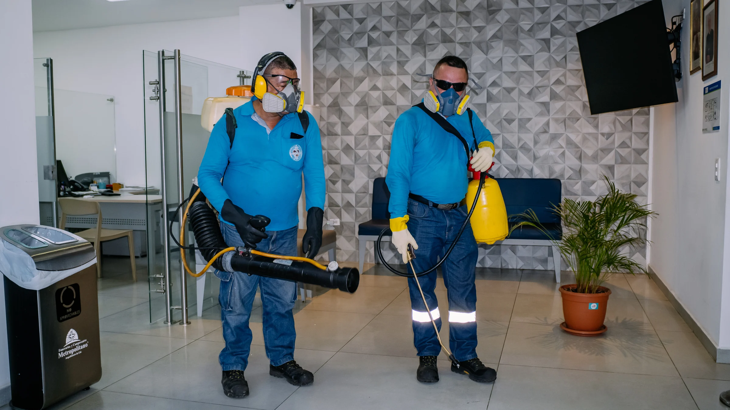Dos tecnicos de control de plagas fumigando unas oficinas en Cali